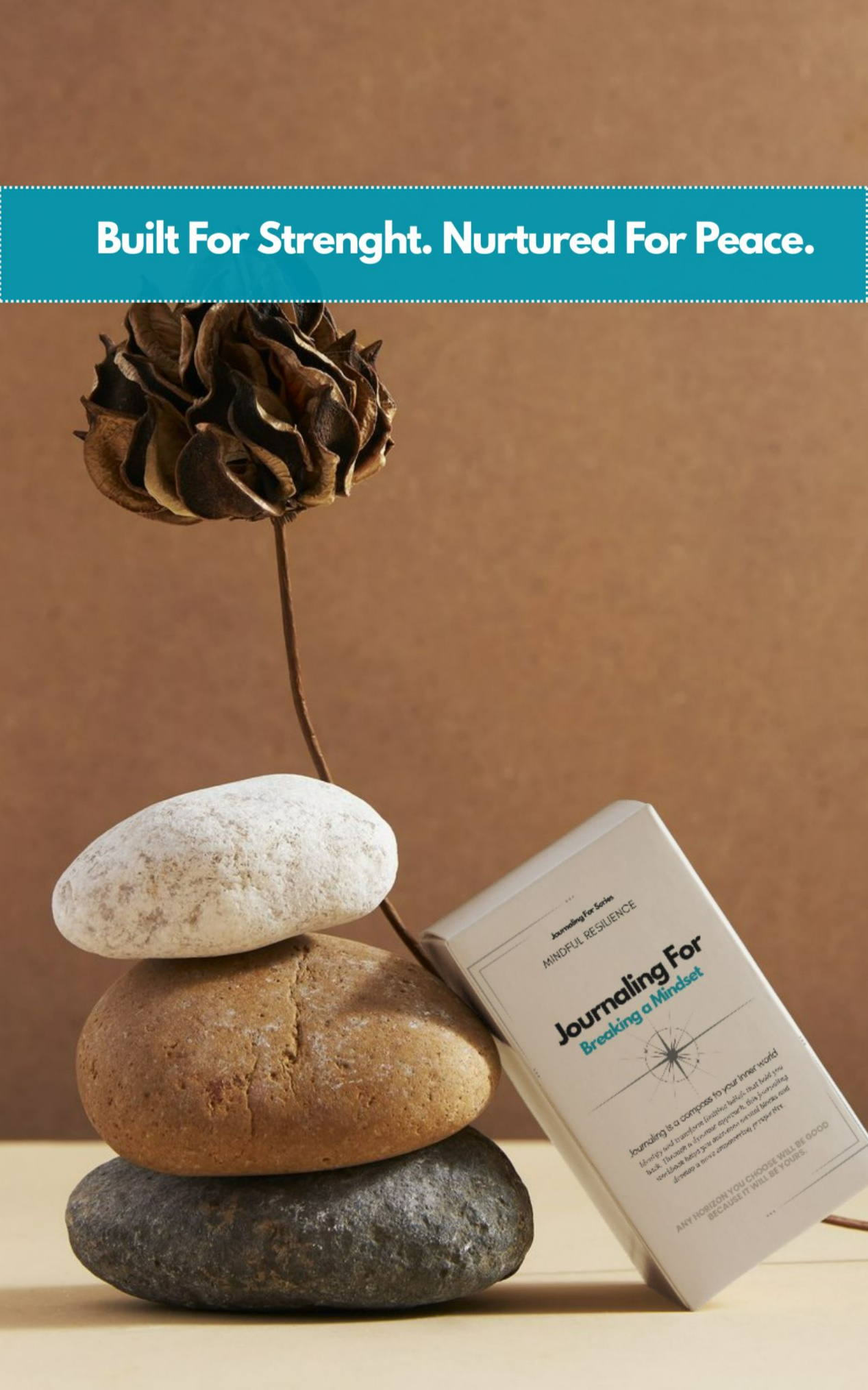 Journaling For – Breaking a Mindset’ workbook placed beside stacked stones and a dried flower, symbolizing the Mindful Resilience category.
